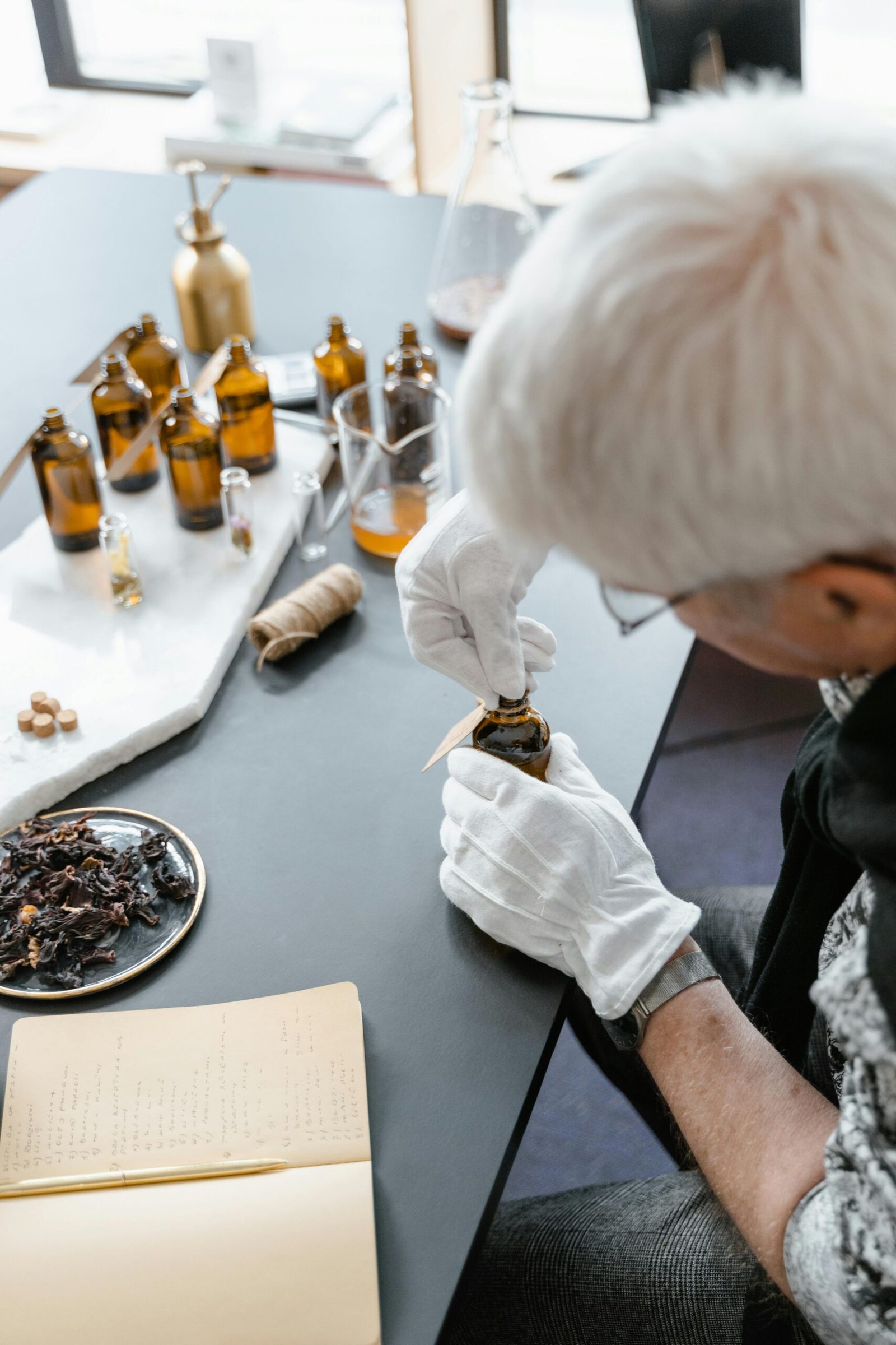 Adult in gloves preparing essential oils for aromatherapy in a workshop setting.